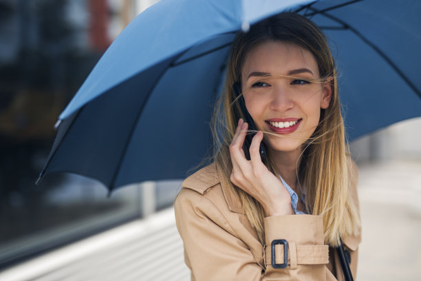在雨天用智能手机吸引年轻女性图片下载