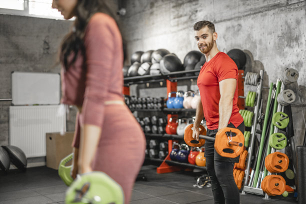 两名年轻运动员在体育馆里交叉练习杠铃锻炼力量图片下载