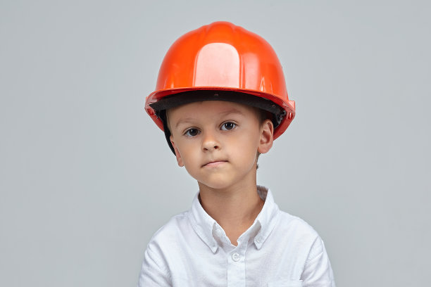 戴着建筑头盔的小男孩。广告概念为建筑。图片下载