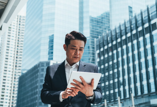 商人使用平板电脑在城市户外与办公大楼在背景库存照片图片下载