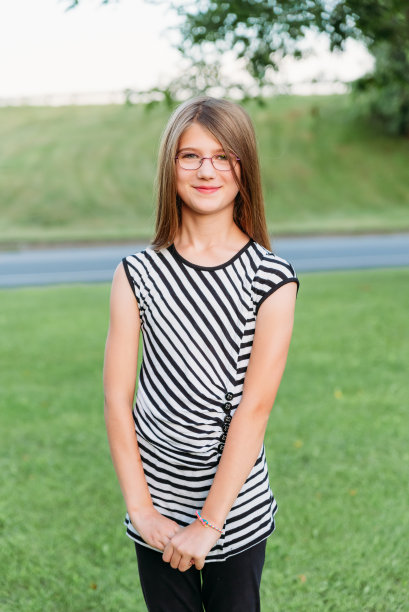 夕阳西下，一名身穿黑白条纹衬衫的少年微笑着站在外面。图片下载