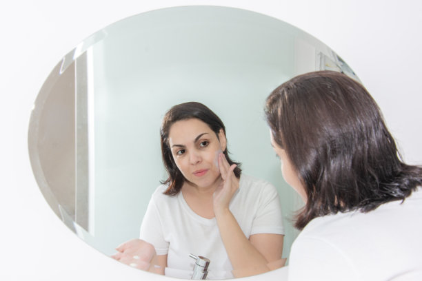 一个女人在镜子前擦面霜图片下载