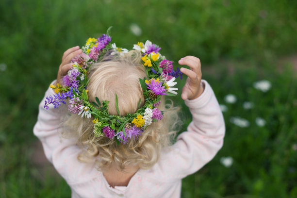 金发小女孩戴着用各种野花编成的五彩花环。Backview图片下载