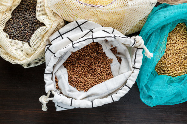 厨房的黑色木桌上放着用可重复使用的棉袋装着的意大利面、大米、荞麦和粗燕麦。“零浪费”的概念。前视图。环保或无塑料的生活理念。图片下载