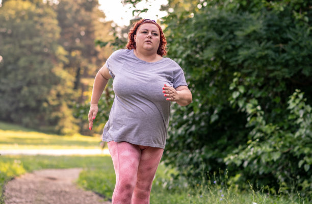 一个肥胖的女人在一个阳光明媚的日子在大自然中慢跑，做减肥训练图片下载