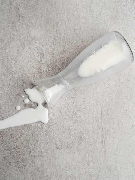 溢出的牛奶，从瓶子溢出的牛奶，牛奶溅在背景上的俯视图，图片下载