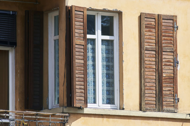 意大利窗在黄色的墙面上，带有开启和关闭的棕色经典百叶窗图片下载