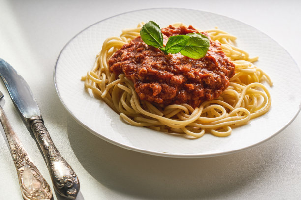 传统的肉酱面放在白色盘子里，用罗勒装饰图片下载