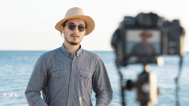 一个年轻人在海边和他的粉丝在社交媒体上视频聊天。科技社交媒体互联网青年概念。图片下载