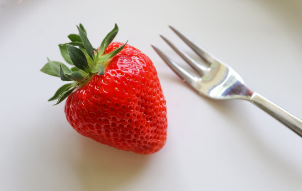 草莓和叶子装在玻璃碗里的盘子里。孤立在白色背景上。图片下载