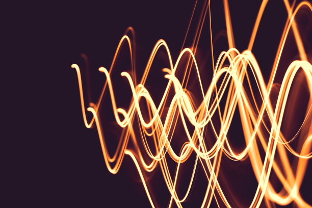 在夜晚用灯光作画，明亮的橙色线条在黑色的背景上。光源在帧内移动。图片下载