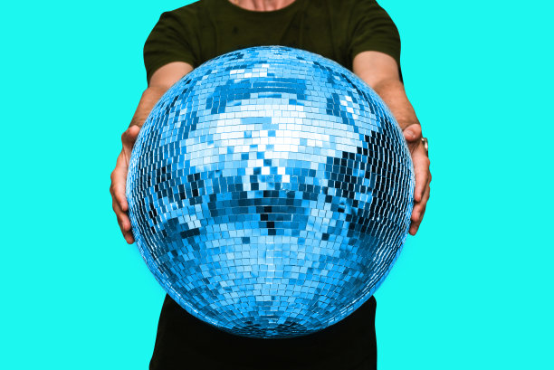 男人手里拿着一个迪斯科球。派对和舞厅的概念。最小的有吸引力的风格图片下载