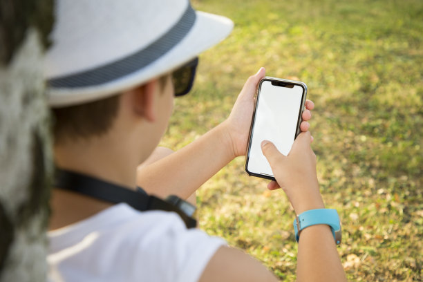 快乐的少年在公园里用手机发短信和上网图片下载