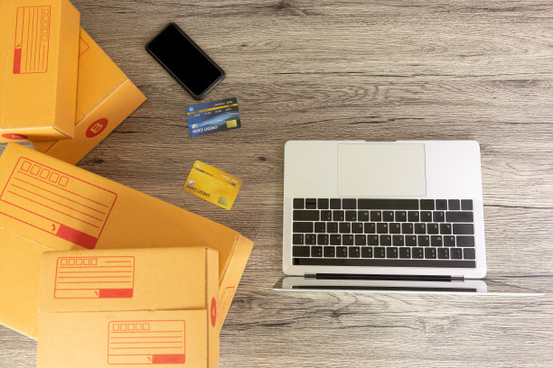 自顶向下的照片与复制空间的笔记本电脑放置在木桌与智能手机，装满盒子和信用卡，用于网上商店购物和电子商务的数字生活方式。图片下载