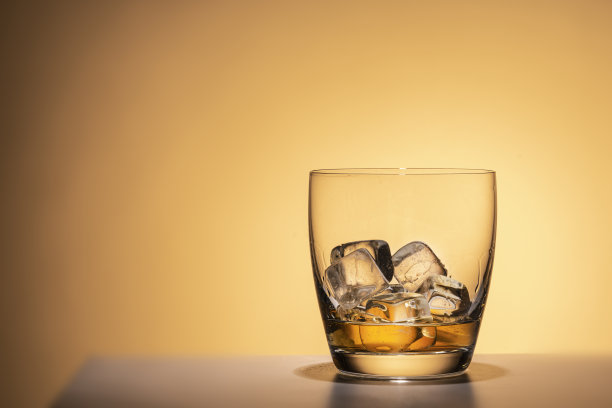 一杯加冰的波旁威士忌、白兰地或利口酒。中心位置，与一个近距离的橙色背景。为酒吧设计。垂直图图片下载