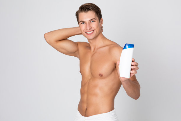 英俊的年轻人站在那里，手里拿着洗发水图片下载