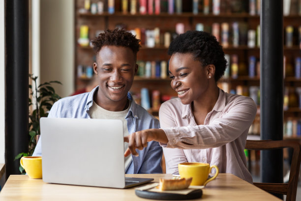 快乐的黑人女孩和她的男朋友一起看电影在咖啡馆的笔记本电脑图片下载