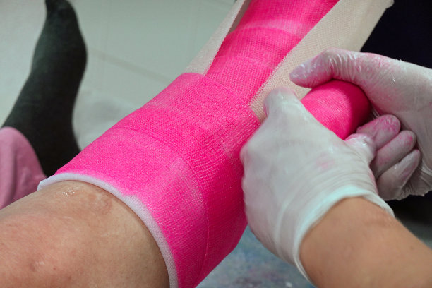 整形。医生用粉红色玻璃纤维将患者骨折的脚踝贴在表层。图片下载