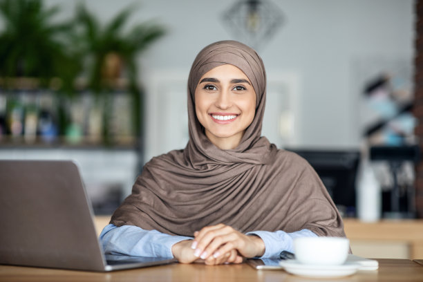 在咖啡馆工作的乐观穆斯林自由职业女孩肖像图片下载