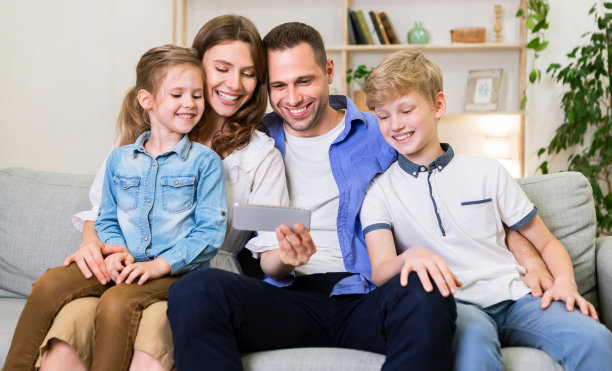 一家四口坐在沙发上玩手机图片下载