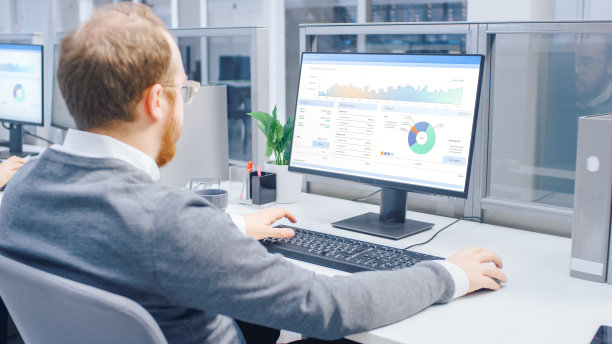 在肩膀上方的照片，积极的商人工作与金融数据，图表和统计的台式电脑。现代大明亮的开放空间办公室图片下载