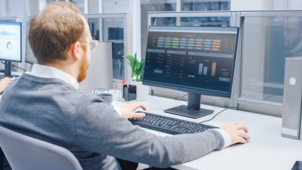 在肩膀上方的照片，积极的商人工作与金融数据，图表和统计的台式电脑。现代大明亮的开放空间办公室图片下载