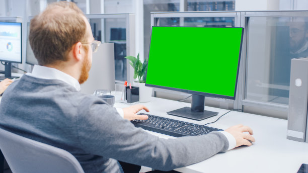 在大明亮的开放空间办公室里，积极的商人在绿色模拟屏幕台式电脑上工作图片下载