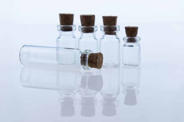 清空用木塞密封的透明小玻璃瓶。物体反射在表面上就像在镜子里一样。宏图片下载