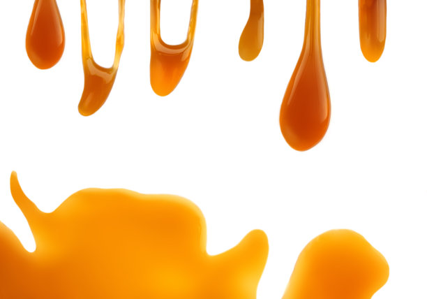 溢出融化的焦糖酱孤立的白色背景。流动的蜂蜜与复制空间。图片下载