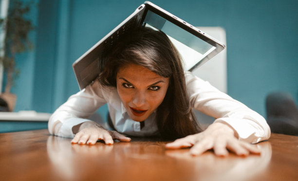 一个疯狂的女商人躺在办公桌上，身上全是笔记本电脑。该去度假了。抗疲劳强度的概念。彩色图像图片下载