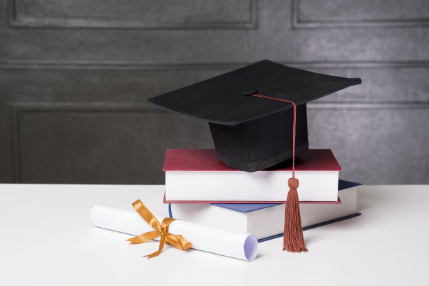 白色课桌上放着毕业帽和书，学历图片下载