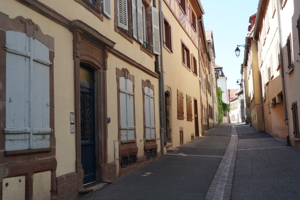 典型的阿尔萨斯式建筑，位于法国科尔马一条用鹅卵石铺成的狭窄街道上。这些房子得到了妥善的维护和居住。两排房子在视野中相交。图片下载