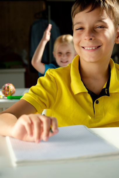 一个男生微笑着坐在书桌前图片下载