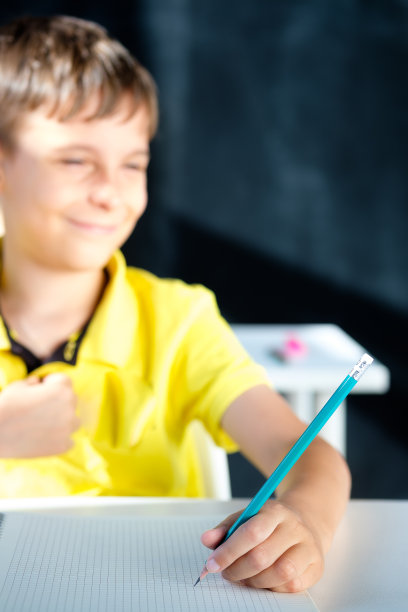 一个男生微笑着坐在书桌前图片下载