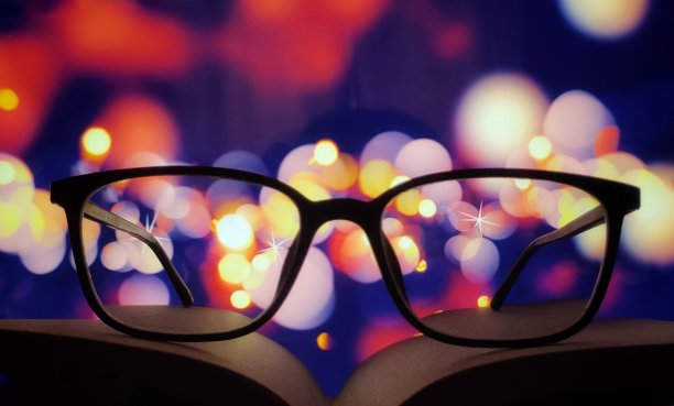 那本书上面戴着眼镜，背景被模糊的灯光照亮了图片下载