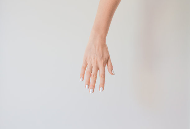 女性的手与美丽的美甲在一个背景的白墙。手部肌肤细腻健康，令手部肌肤焕发活力，滋润呵护图片下载