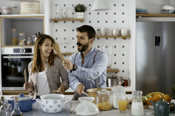 快乐的夫妇有乐趣，跳舞和唱歌在厨房在家里的上午库存照片图片下载