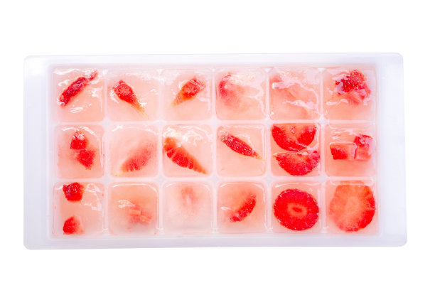 红草莓切片冰，冻结在塑料托盘，俯视图照片孤立在白色背景图片下载