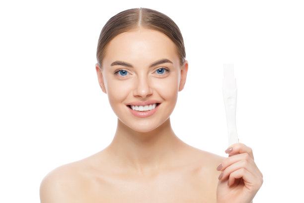 特写年轻美丽的蓝眼睛的女性，站着赤裸的肩膀，抱着怀孕测试，感觉幸福，孤立在白色的背景图片下载