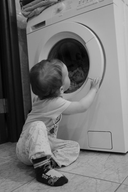 小孩站在洗衣机旁边按按钮图片下载