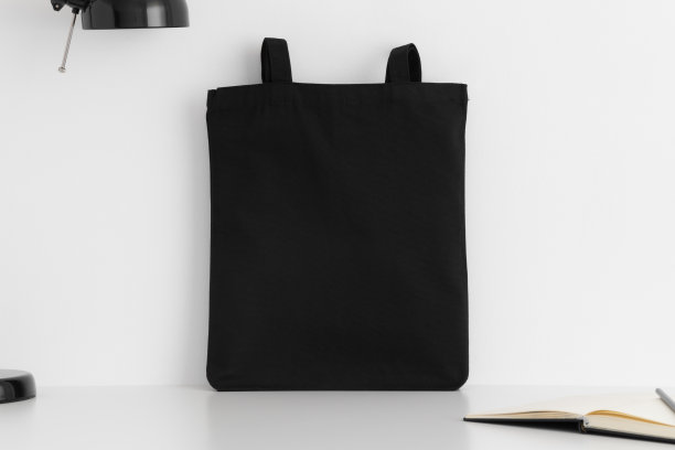黑色手提袋模型与工作配件在白色桌子上。图片下载