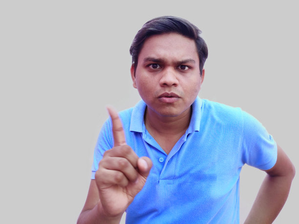 身穿T恤的男子在灰色背景下好奇地展示了一号手指图片下载