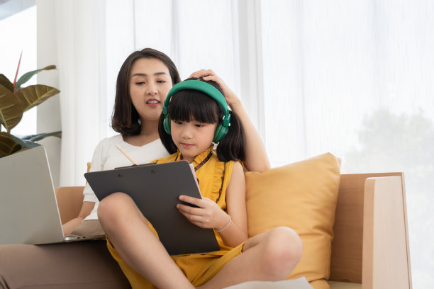 亚洲年轻的母亲用电脑笔记本教孩子学习或学习在家里，在家教育在线的概念图片下载