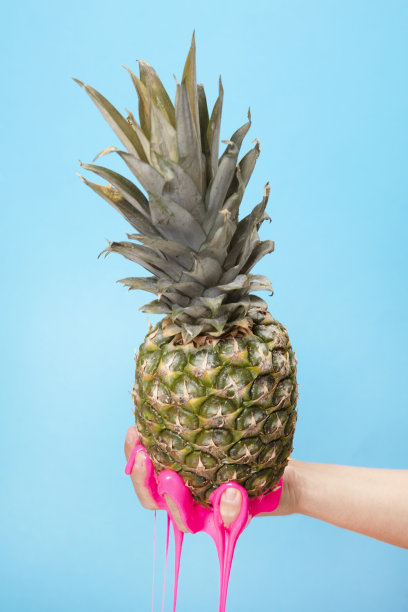 手拿菠萝切片在蓝色的纸背景。图片下载