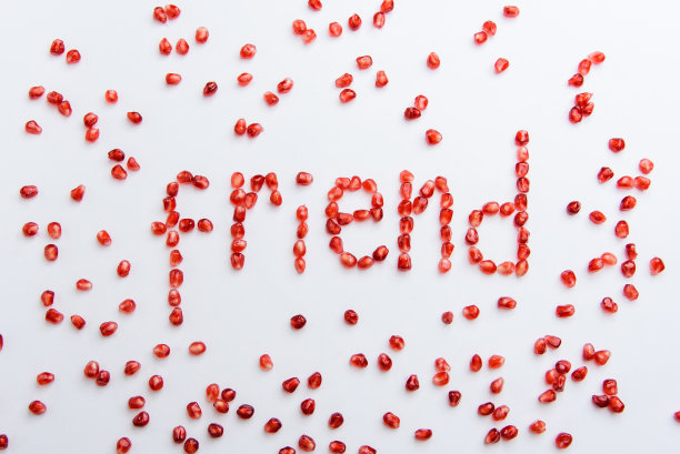 白色背景上的石榴籽上的“朋友”一词图片下载