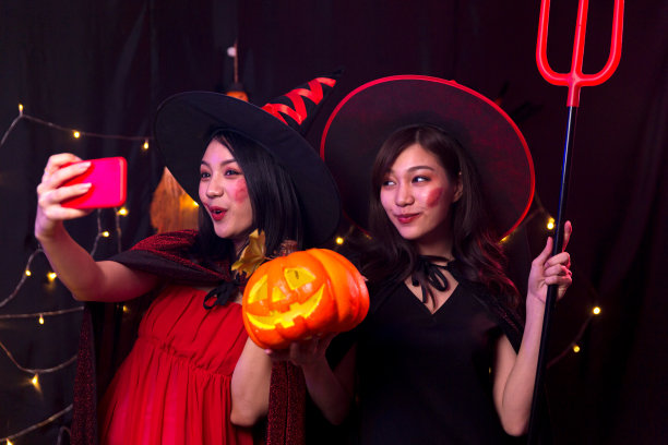万圣节派对上，两个女人用手机拍照。在派对上用手机自拍。图片下载