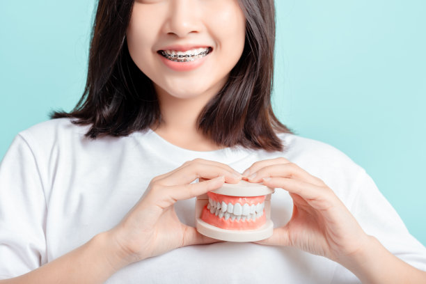 牙套亚洲妇女戴牙套与牙齿样本和白牙齿增加信心健康在蓝色背景孤立工作室拍摄，快乐青少年微笑的面部表情。图片下载