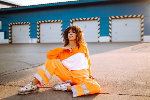 美丽的非洲裔美国女人，一头卷发，穿着橙色的衣服。图片下载