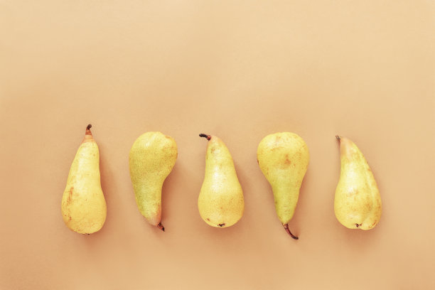 黄色的梨子，米色背景，俯视图，平铺图片下载