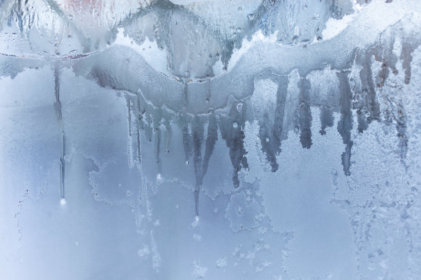 冬天融化的霜冻图案冻住了白色的窗户玻璃。图片下载